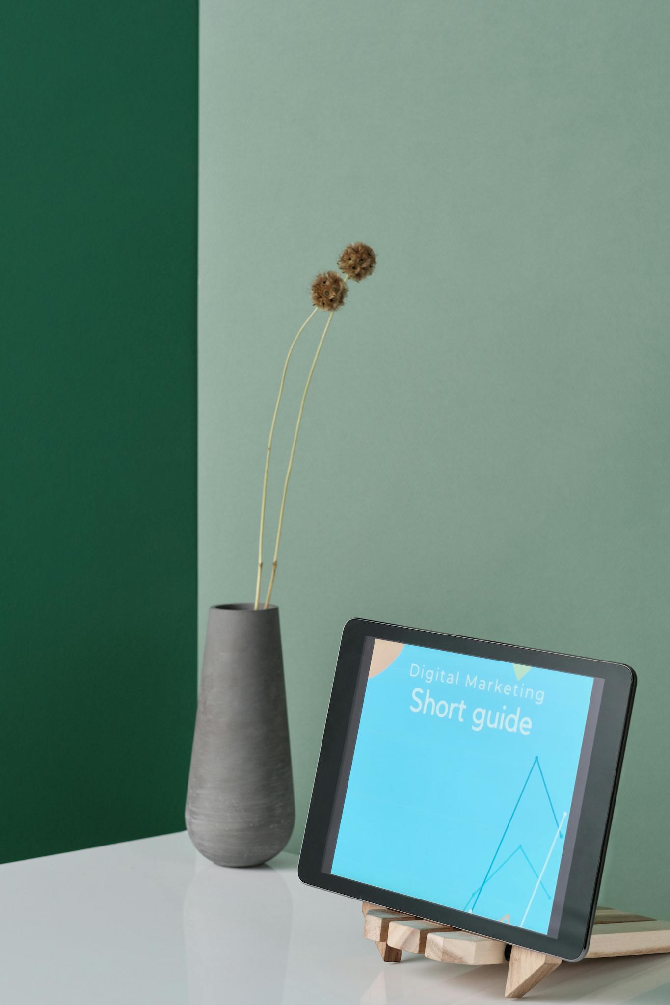 A sleek workspace featuring a tablet on a stand alongside a modern vase.