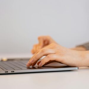 Hands typing on a laptop keyboard, focusing on digital connectivity and remote work.